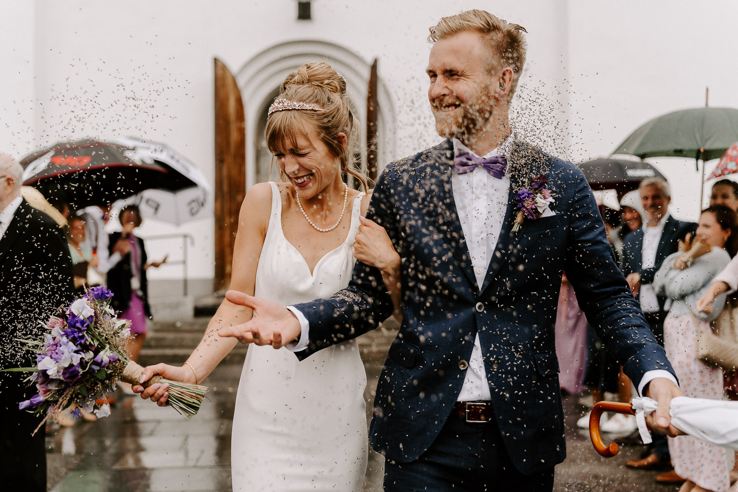 Glatt brudpar utanför kyrkan iJärvsö i ett regn av blomsterkonfetti